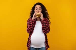 Femme enceinte qui mange un burger