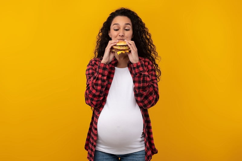 Femme enceinte qui mange un burger