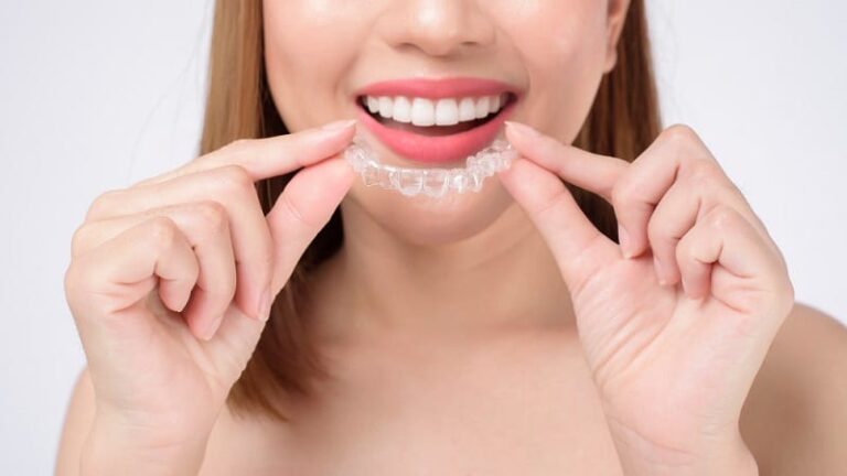 jeune femme souriante tenant des attaches invisibles dentaire soins orthodontiques